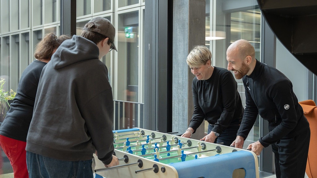 Vier Personen am Tischfussball spielen und lachen