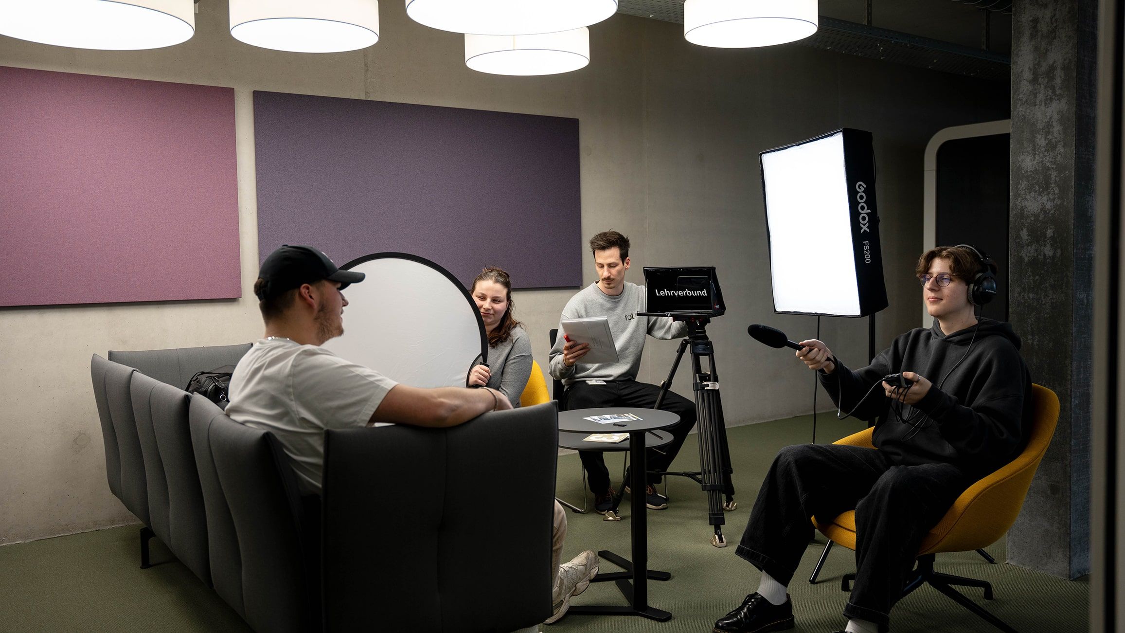 Quattro studenti filmano un'intervista con telecamera, luci e audio